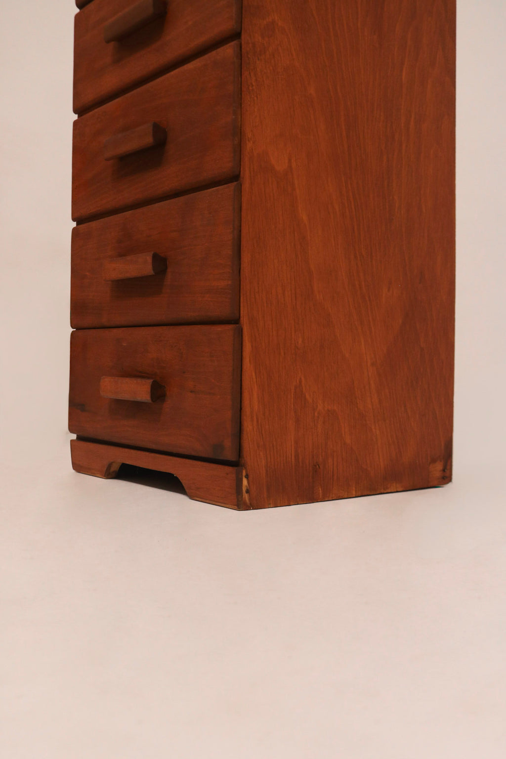 Angled view of single chest of drawers highlighting narrow profile and height