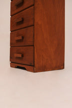 Angled view of single chest of drawers highlighting narrow profile and height