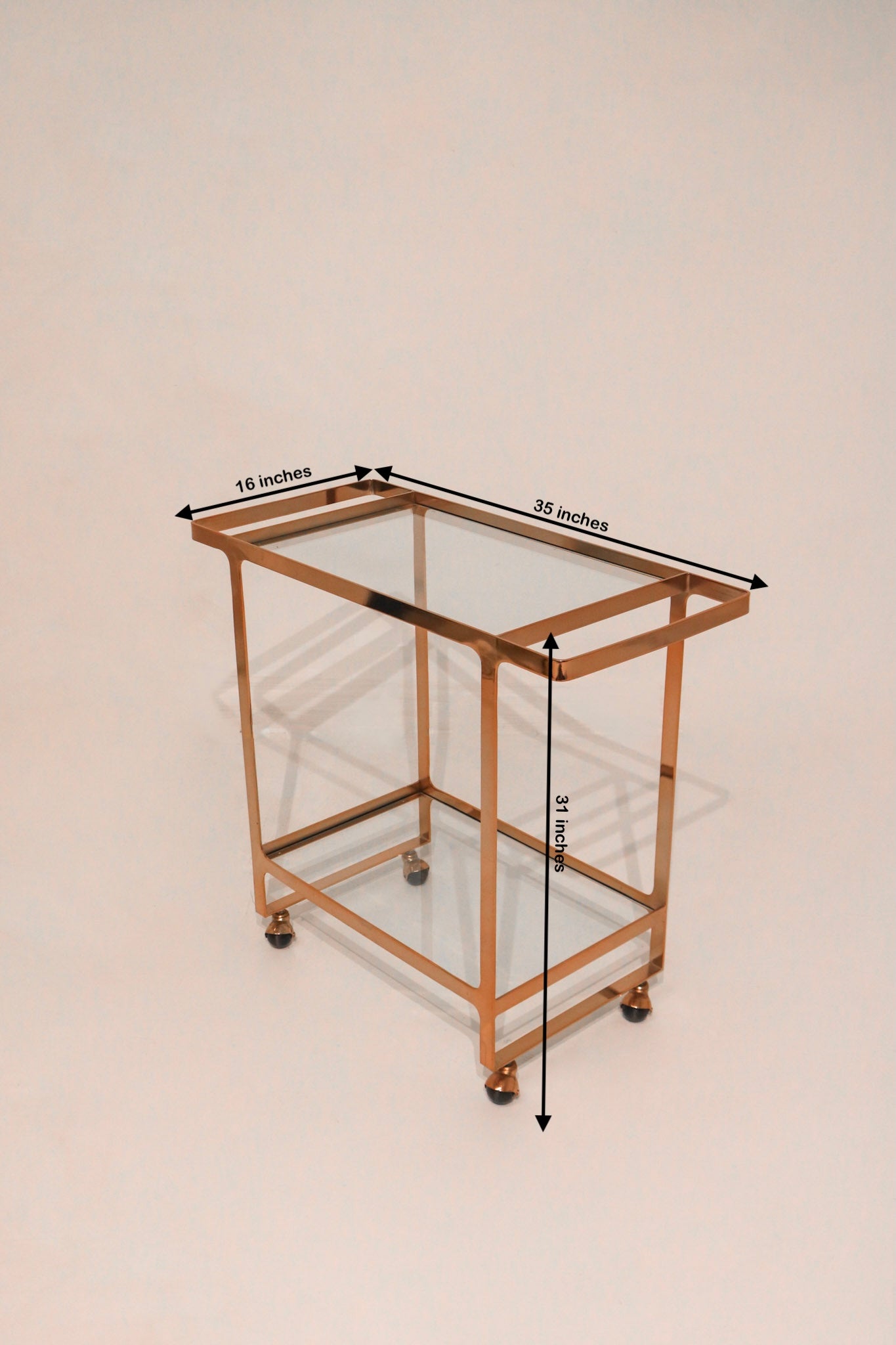 Top-down angled view of bar cart showing glass shelves and rose gold frame