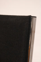 Close-up edge of black fabric seat attached to chrome steel support