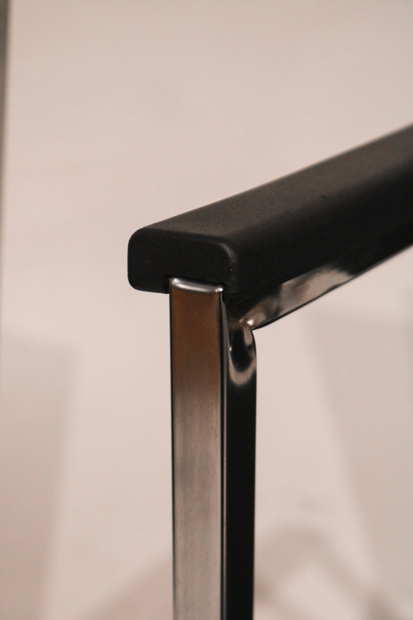 Chrome armrest detail highlighting black fabric upholstery on steel frame