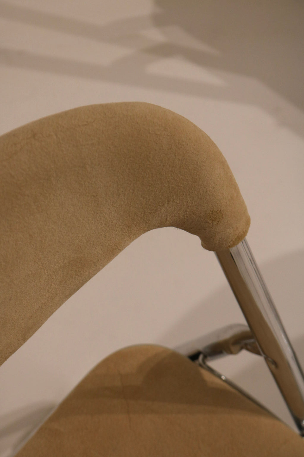 Detail of curved upholstered backrest attached to chrome tubular frame