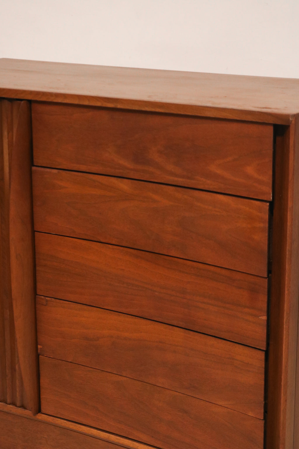 Close-up of the curved drawer fronts showing matched walnut grain