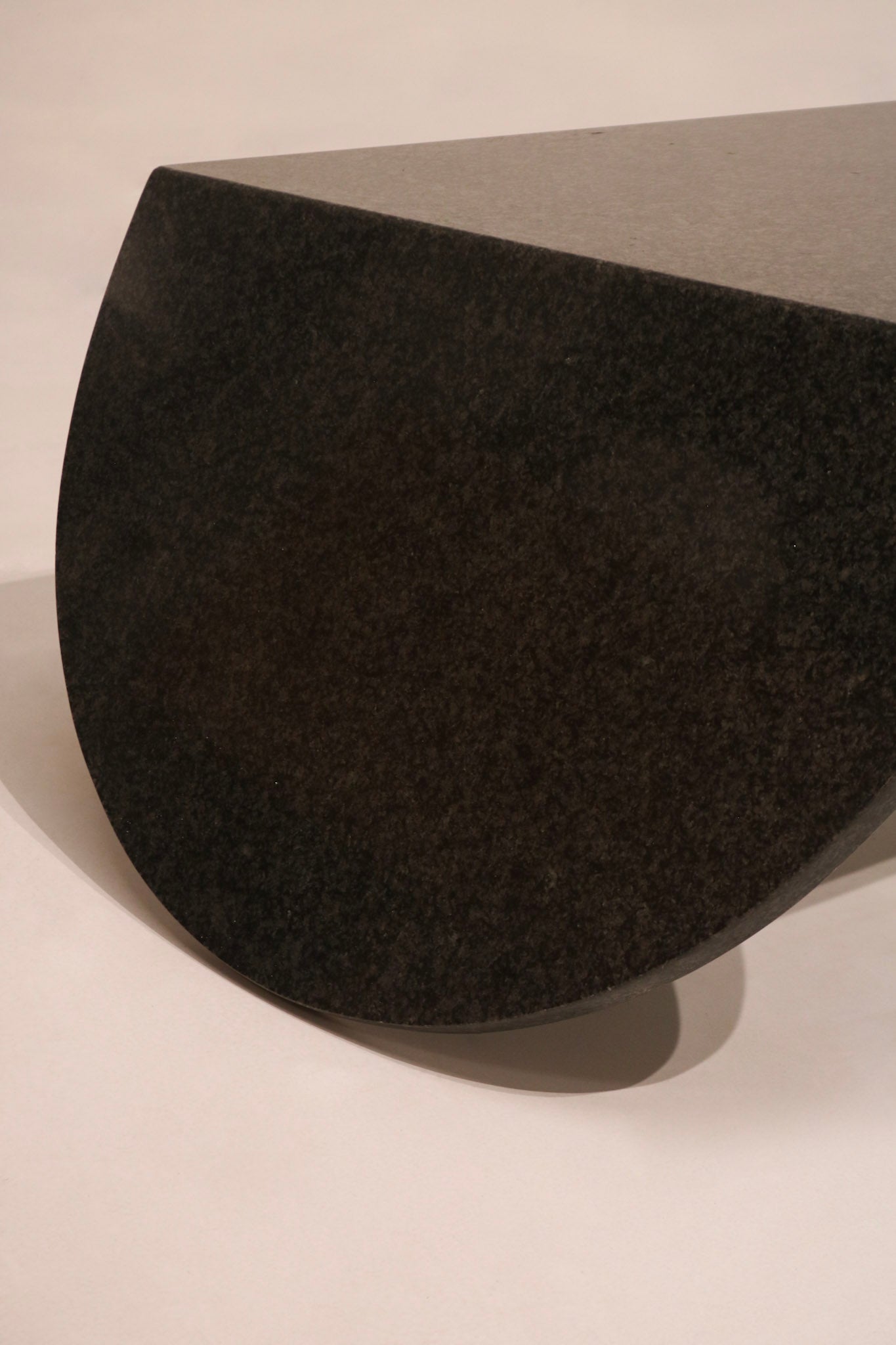 Close-up detail of curved waterfall edge on black stone coffee table base