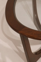 Detail of curved wood leg supporting the glass top with elegant lines