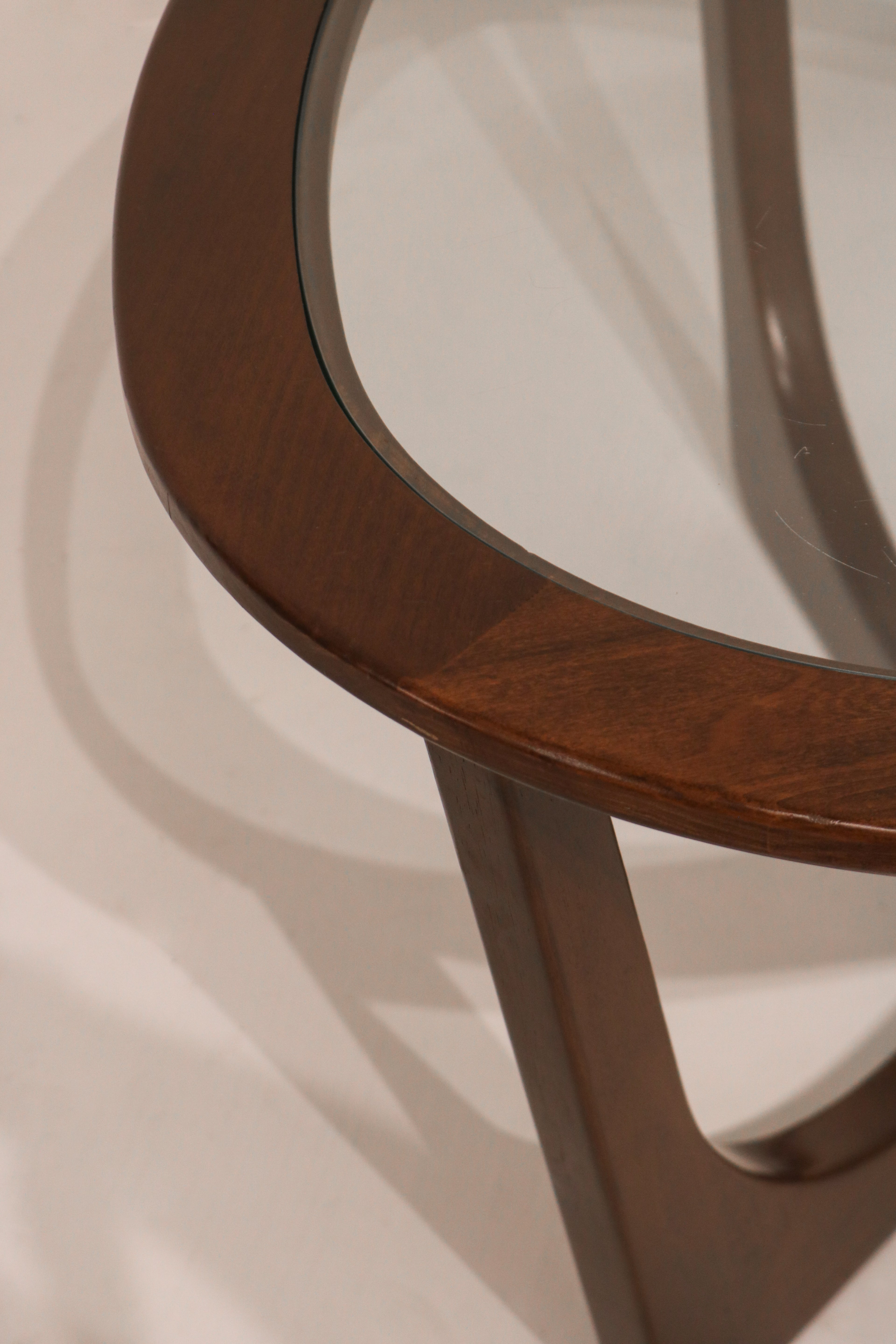 Detail of curved wood leg supporting the glass top with elegant lines