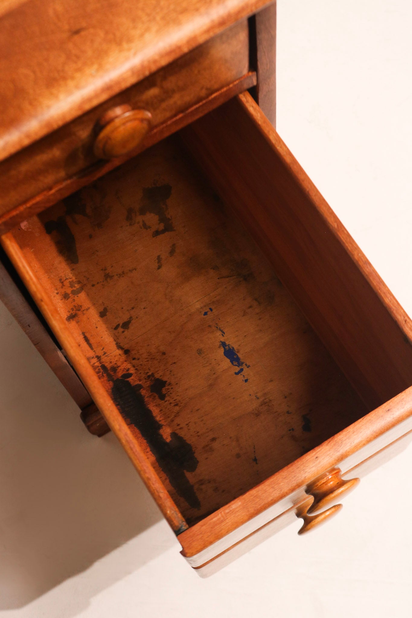 Bottom corner of desk showing wear consistent with vintage wooden furniture
