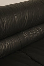 Detail of the armrest on the vintage Italian leather couch, highlighting curved design and fine leather