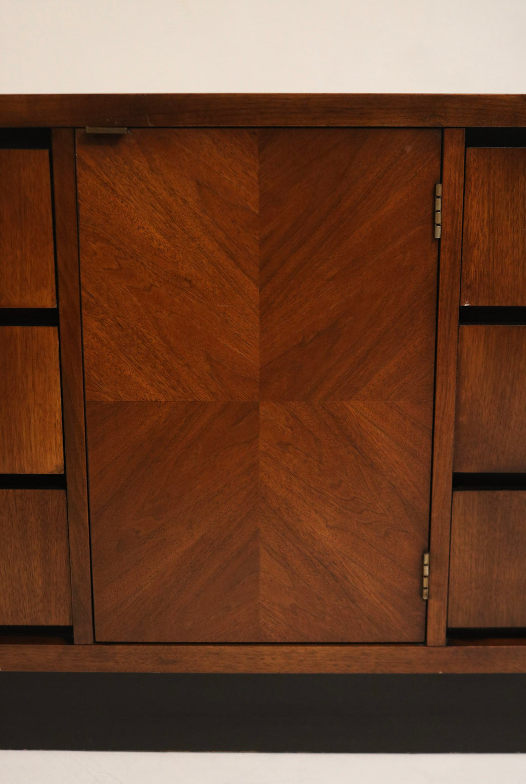 Angle view of three drawers closed, showing consistent walnut finish, recessed pulls and sculpted mid-century form in solid wood