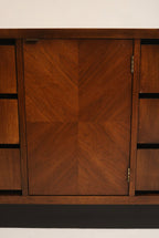 Angle view of three drawers closed, showing consistent walnut finish, recessed pulls and sculpted mid-century form in solid wood