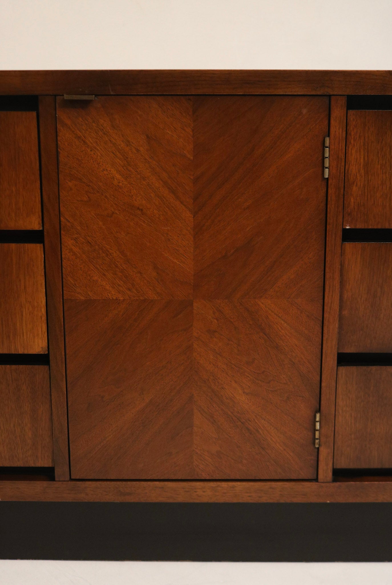 Angle view of three drawers closed, showing consistent walnut finish, recessed pulls and sculpted mid-century form in solid wood