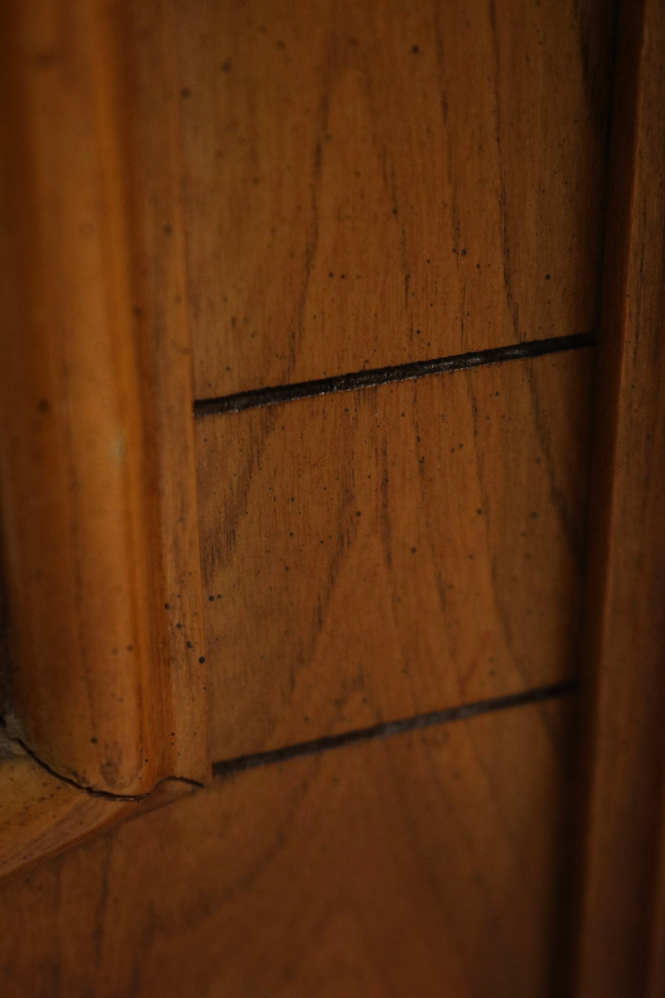 Top edge close-up of oak wood frame showing finish loss, worn lacquer, light scratches and patina, reflecting vintage wear.