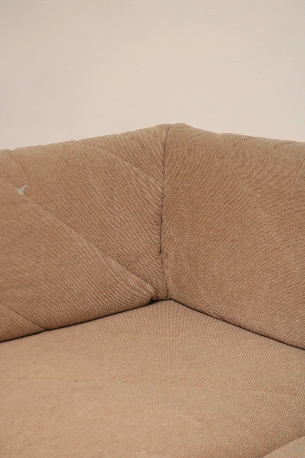 Close view of back cushion upholstery on Mcm sectional fabric sofa highlighting tufting, stitching and fabric grain in warm brown tone