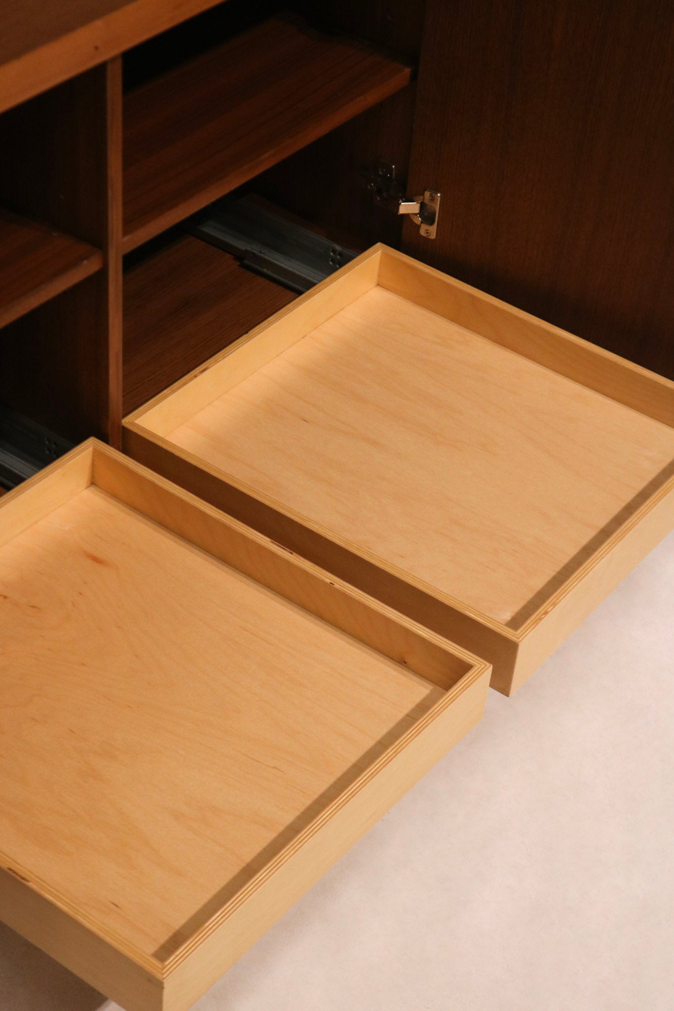Close-up of credenza legs, featuring brushed metal finish for contrast with warm wood