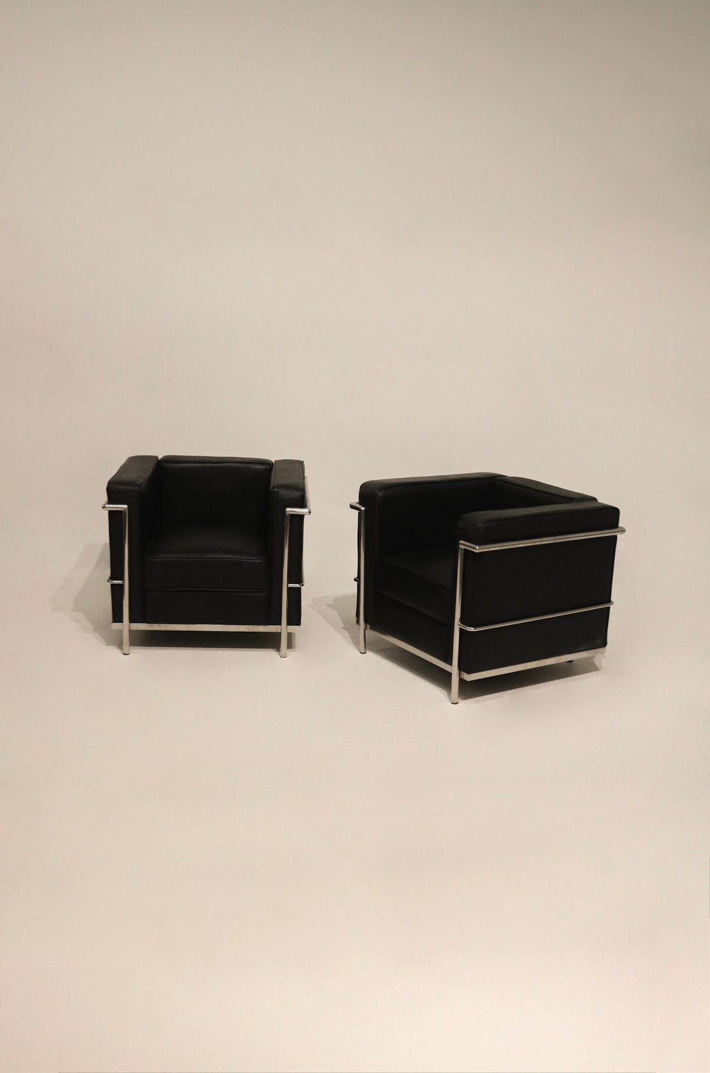 Black leather and chrome LC2 Petit Modele armchairs, full view of both chairs in modern NYC interior