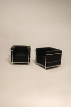 Black leather and chrome LC2 Petit Modele armchairs, full view of both chairs in modern NYC interior