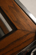 Shelf detail of bookcase showing layering of materials—glass above wood supported by chrome rods