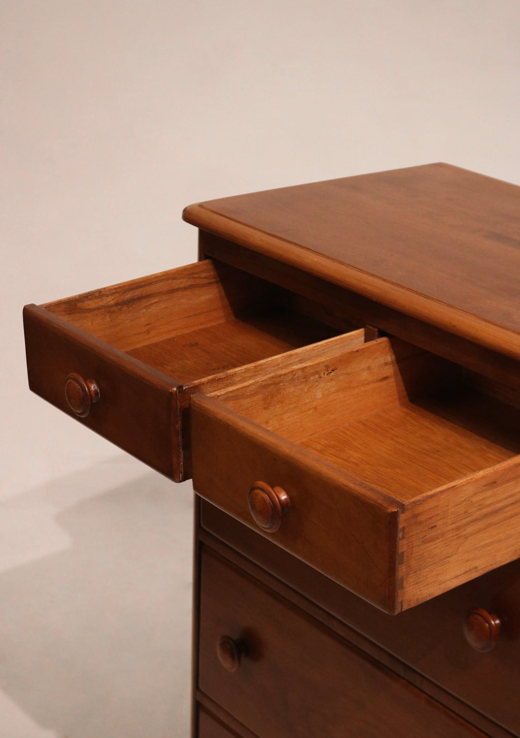 Low angle view capturing highboy’s tall structure and warm wood finish
