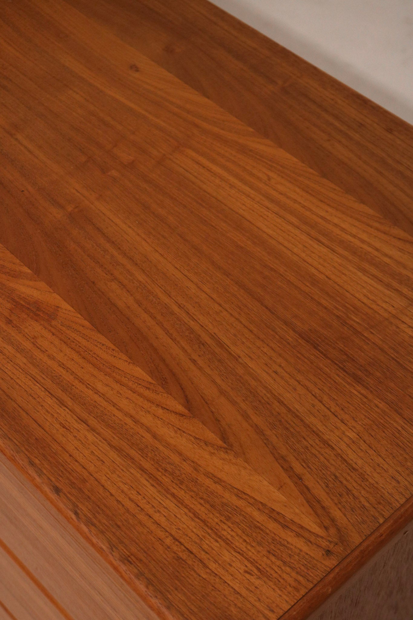 Corner close-up highlighting the smooth teak finish and edge contours of the dresser
