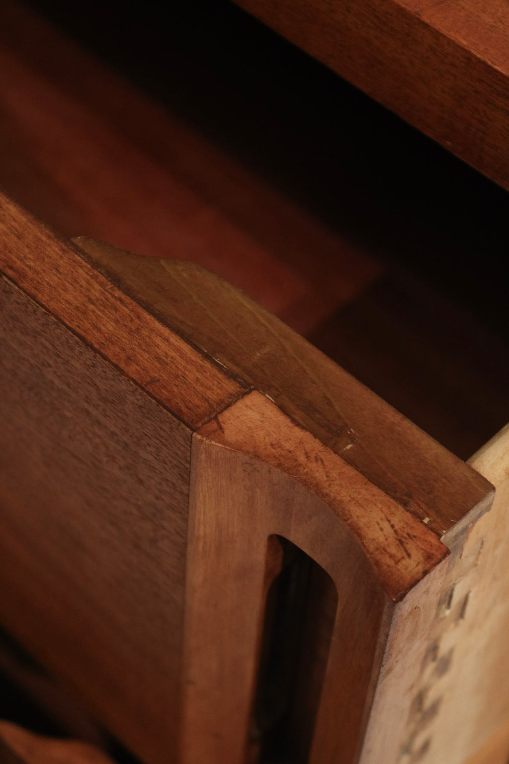 Detail image of finish variations and touch marks on stained walnut solid wood dresser, authentic vintage patina and sanded surface