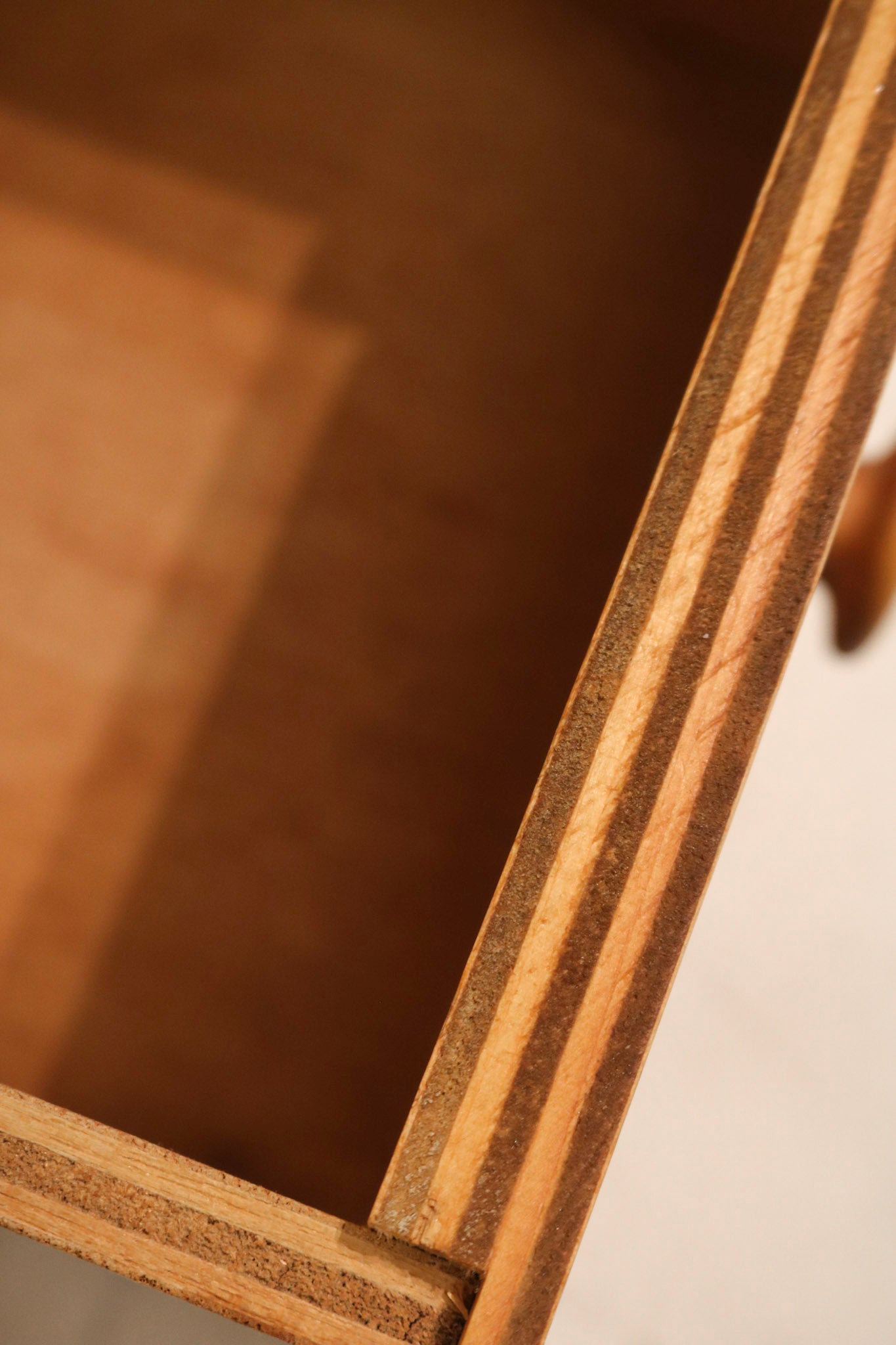 Angled side view of slim vertical oak storage cabinet with smooth finish