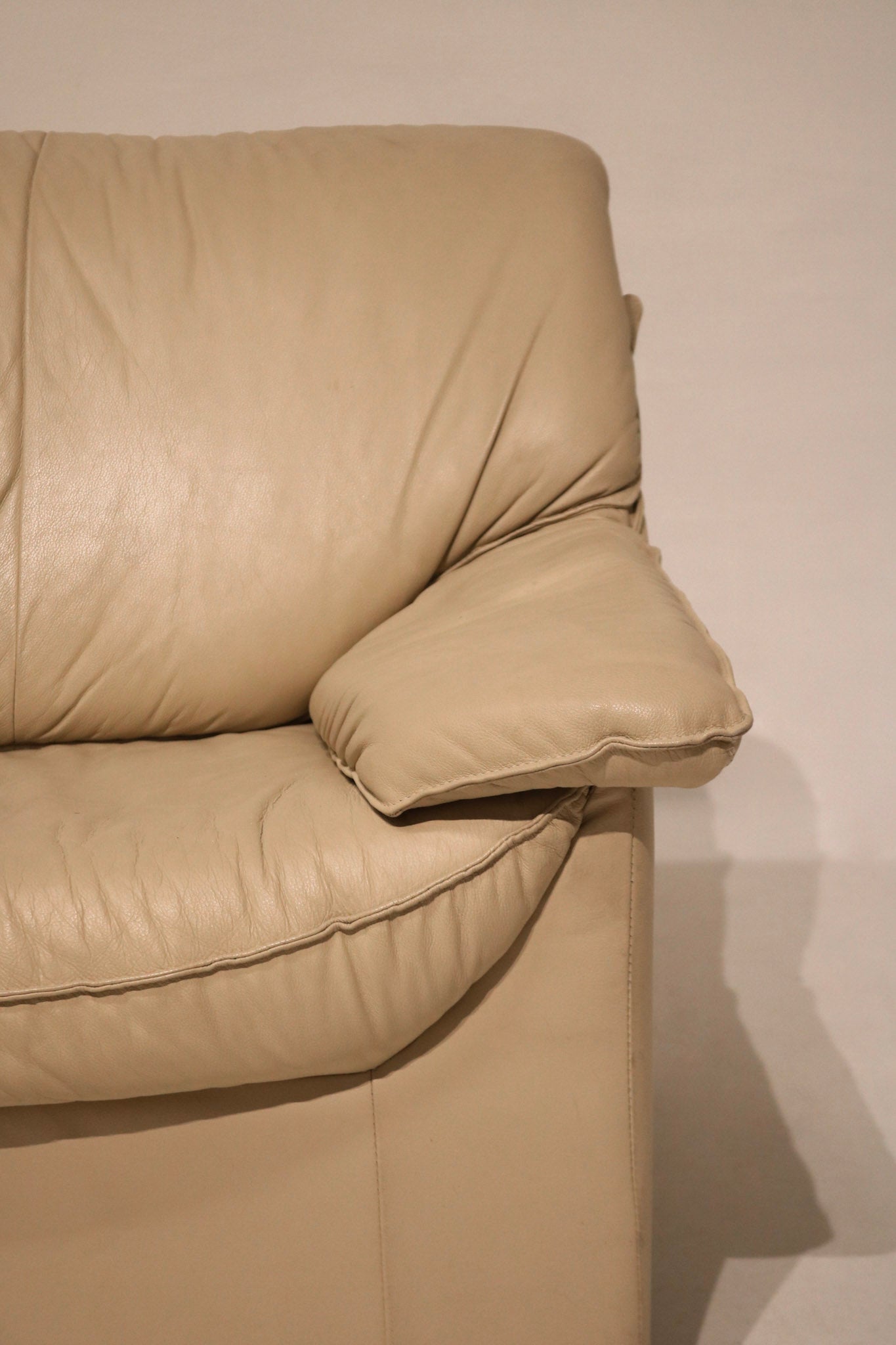 Close-up of backrest cushions on beige leather vintage couch, plush and well-shaped