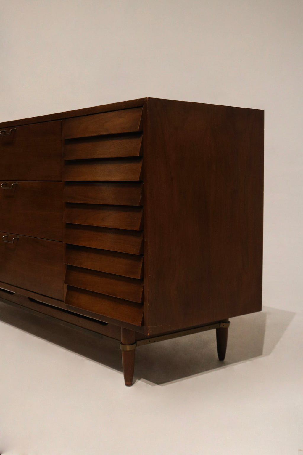 Hardware close-up showing original drawer pulls and fasteners with vintage patina on walnut facade
