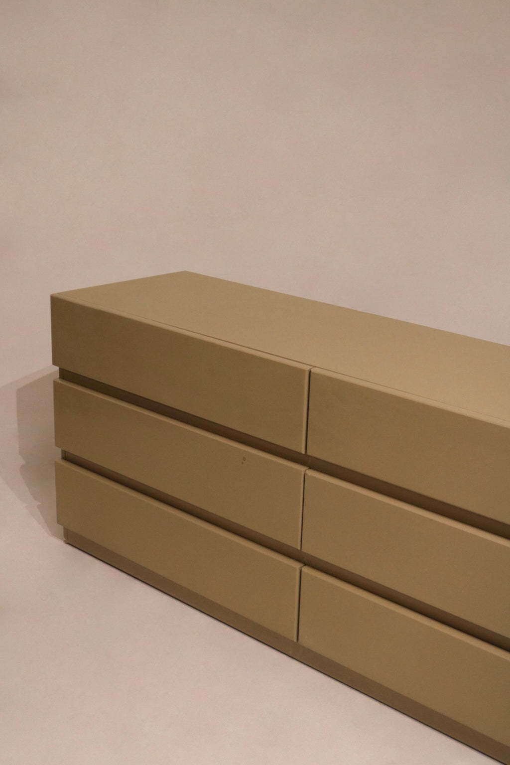 Angled shot capturing dresser's height and depth along taupe wood grain texture