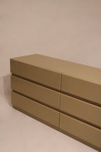 Angled shot capturing dresser's height and depth along taupe wood grain texture