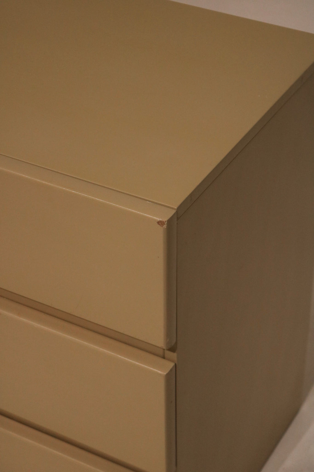 Vintage handle detail in brushed brass finish contrasting against lacquered taupe drawer face