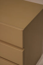 Vintage handle detail in brushed brass finish contrasting against lacquered taupe drawer face