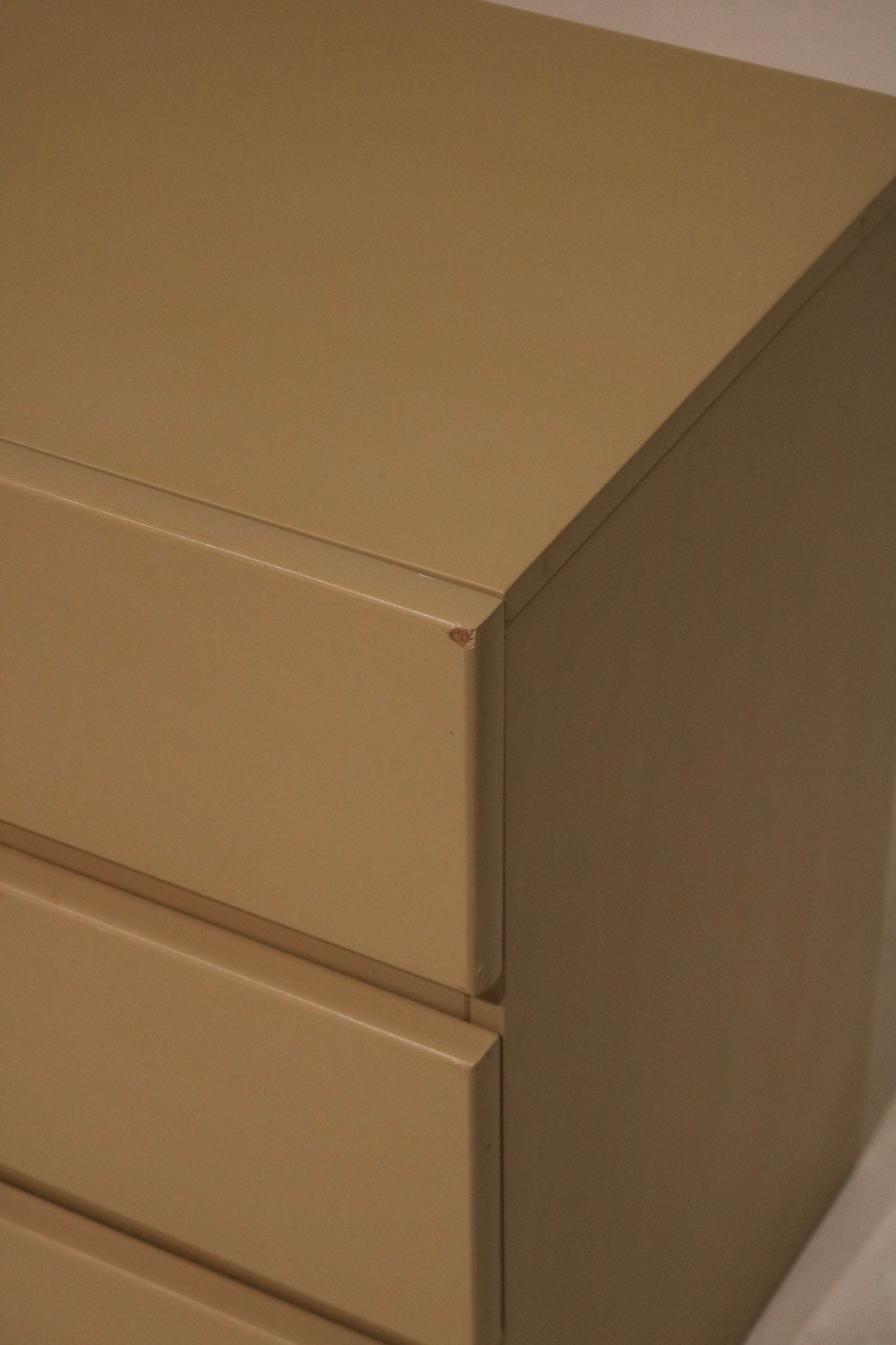 Vintage handle detail in brushed brass finish contrasting against lacquered taupe drawer face