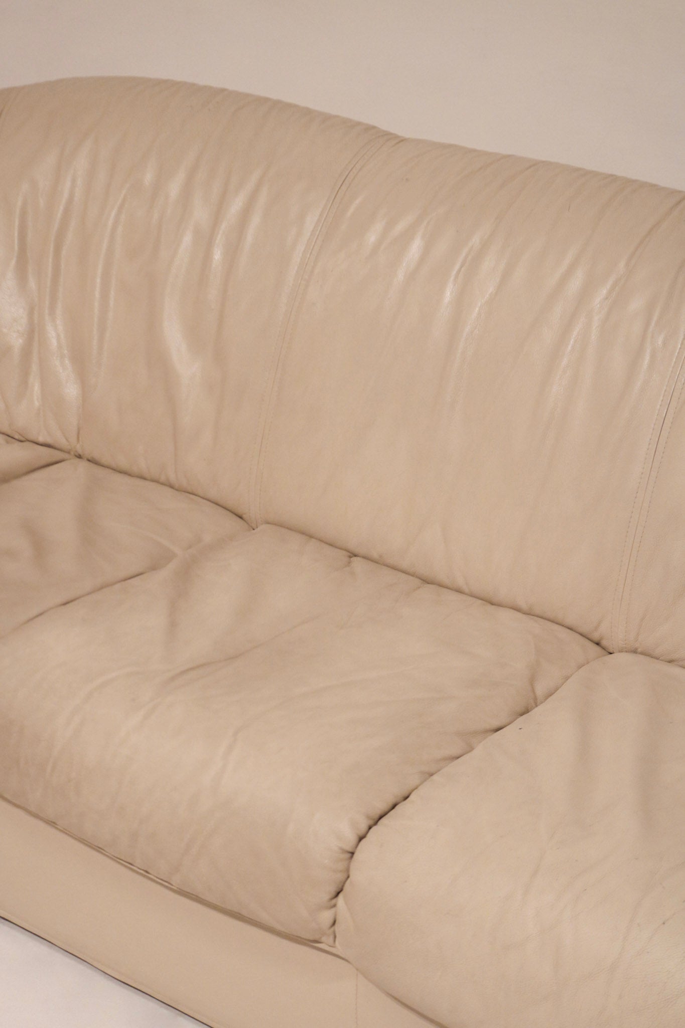 Detailed image of tiny hole close-up in beige leather upholstery of Natuzzi sofa