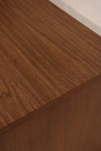 Close-up of top veneer surface on dresser with light usage marks and walnut wood detailing