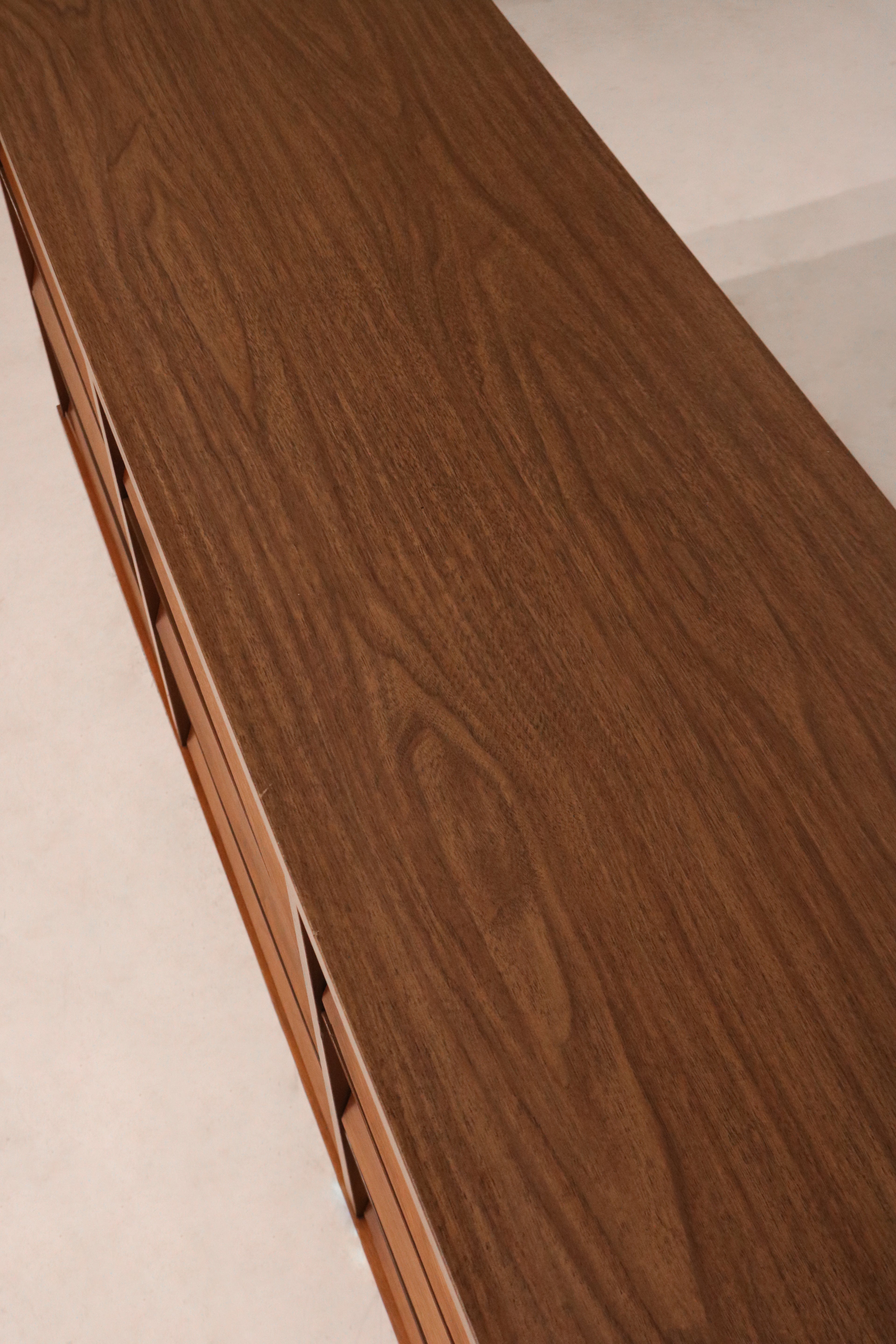 Angled side view of Johnson Carper dresser showing all 9 drawers and rich walnut wood tones