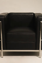 Armrest detail of chrome frame and black faux leather padding on LC2 lounge chair