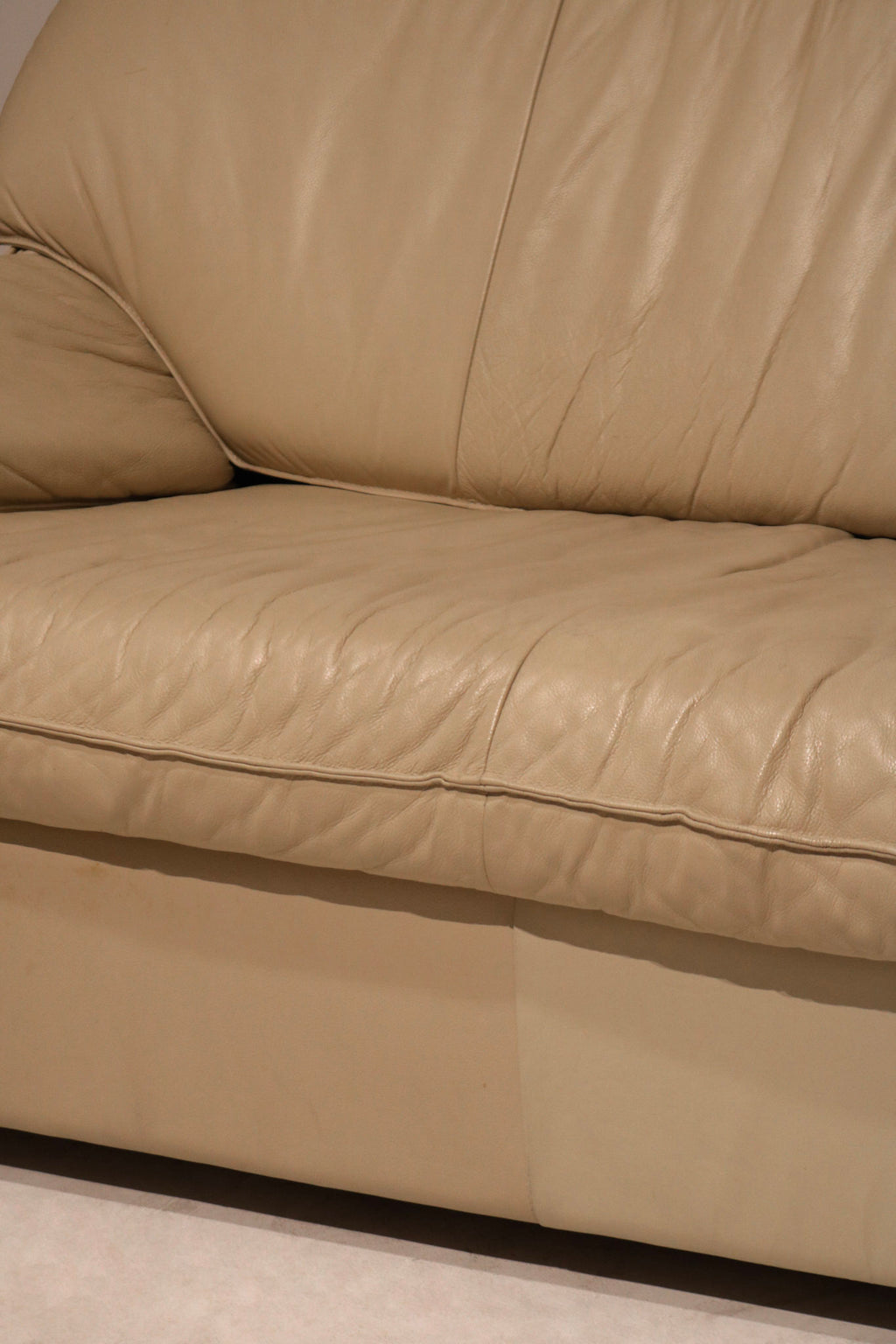 Detail shot of sofa armrest in real Italian leather, showcasing flawless beige upholstery