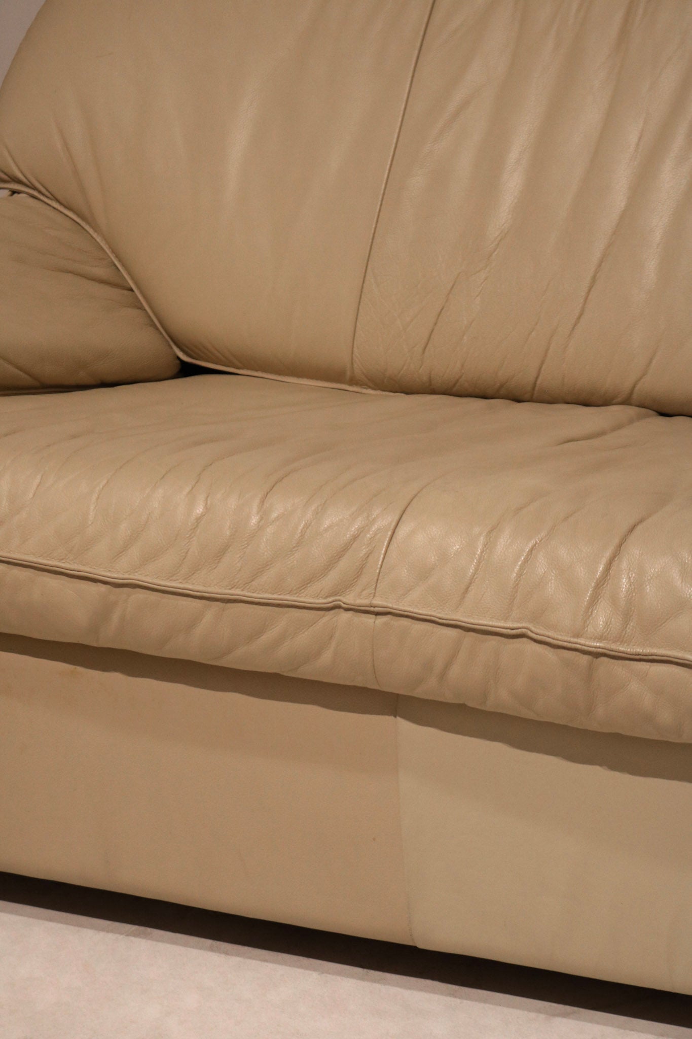 Detail shot of sofa armrest in real Italian leather, showcasing flawless beige upholstery