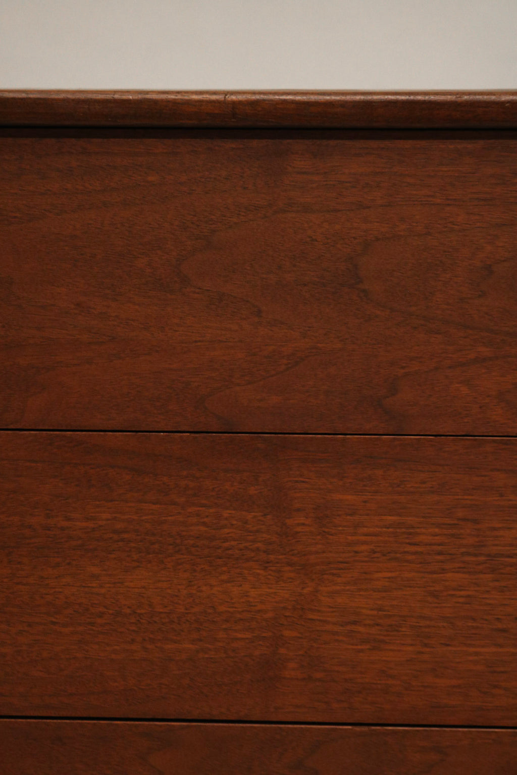 Detail of one drawer's handle on Mcm walnut dresser showing solid wood and vintage pull