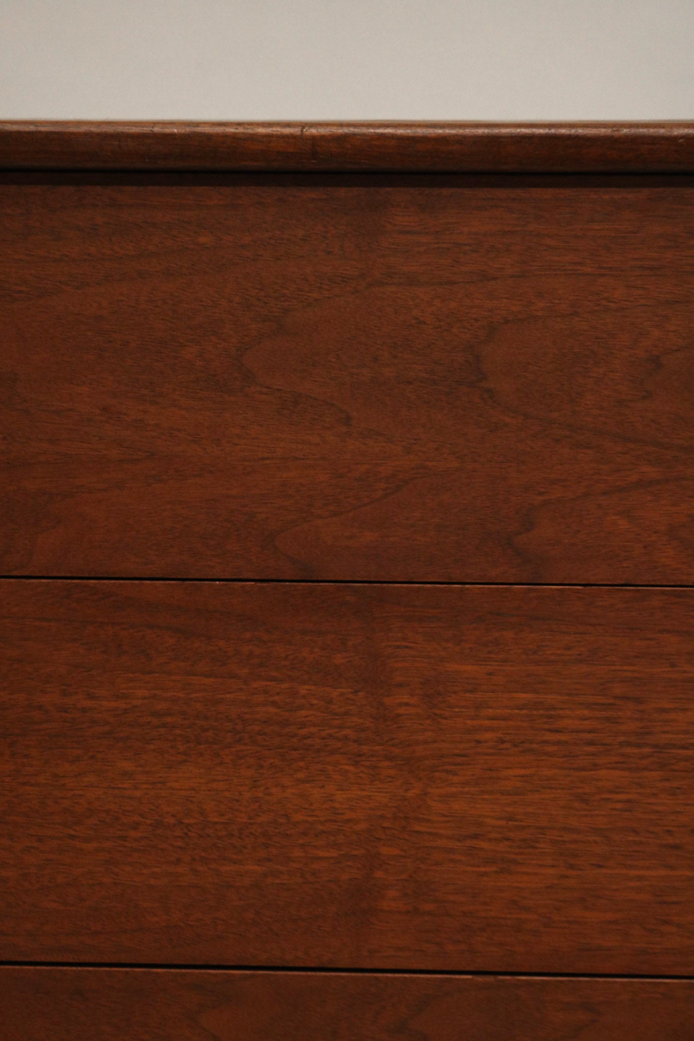 Detail of one drawer's handle on Mcm walnut dresser showing solid wood and vintage pull