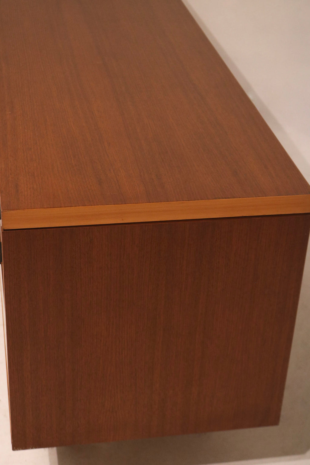 Close-up of nick on left front corner of walnut cabinet highlighting minor wear