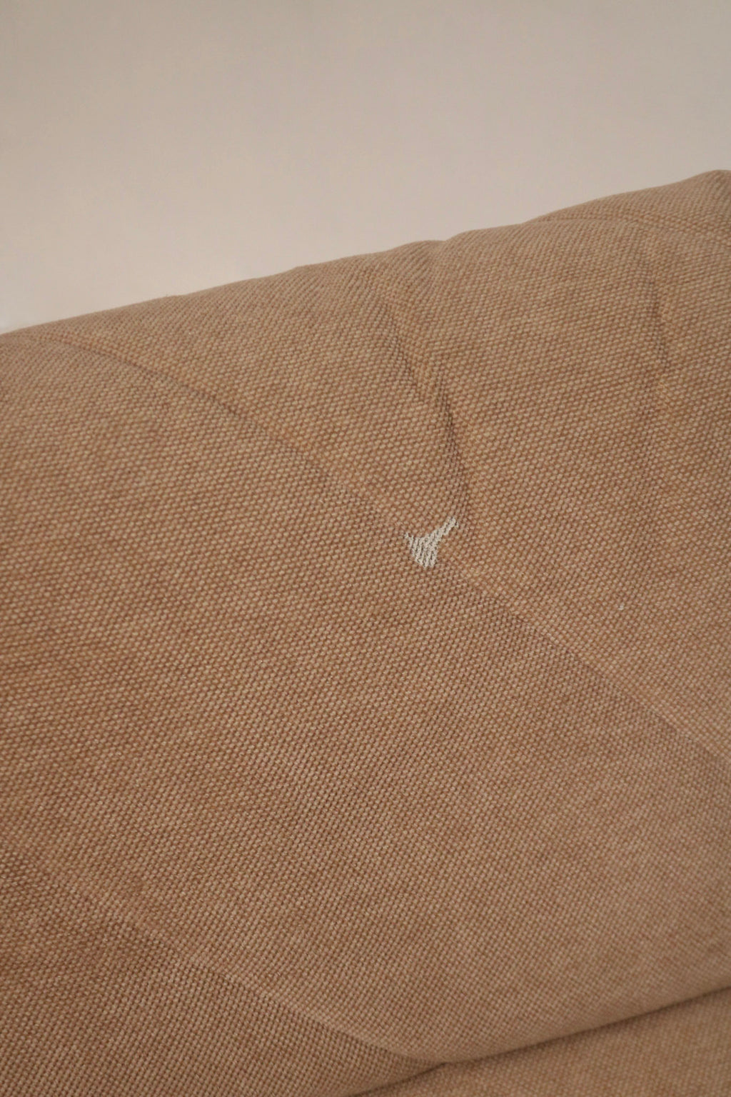 Detail shot of seat cushion edge on fabric modular sofa showing piping, seam construction and plush fabric surface in brown-pink material