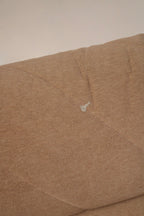 Detail shot of seat cushion edge on fabric modular sofa showing piping, seam construction and plush fabric surface in brown-pink material
