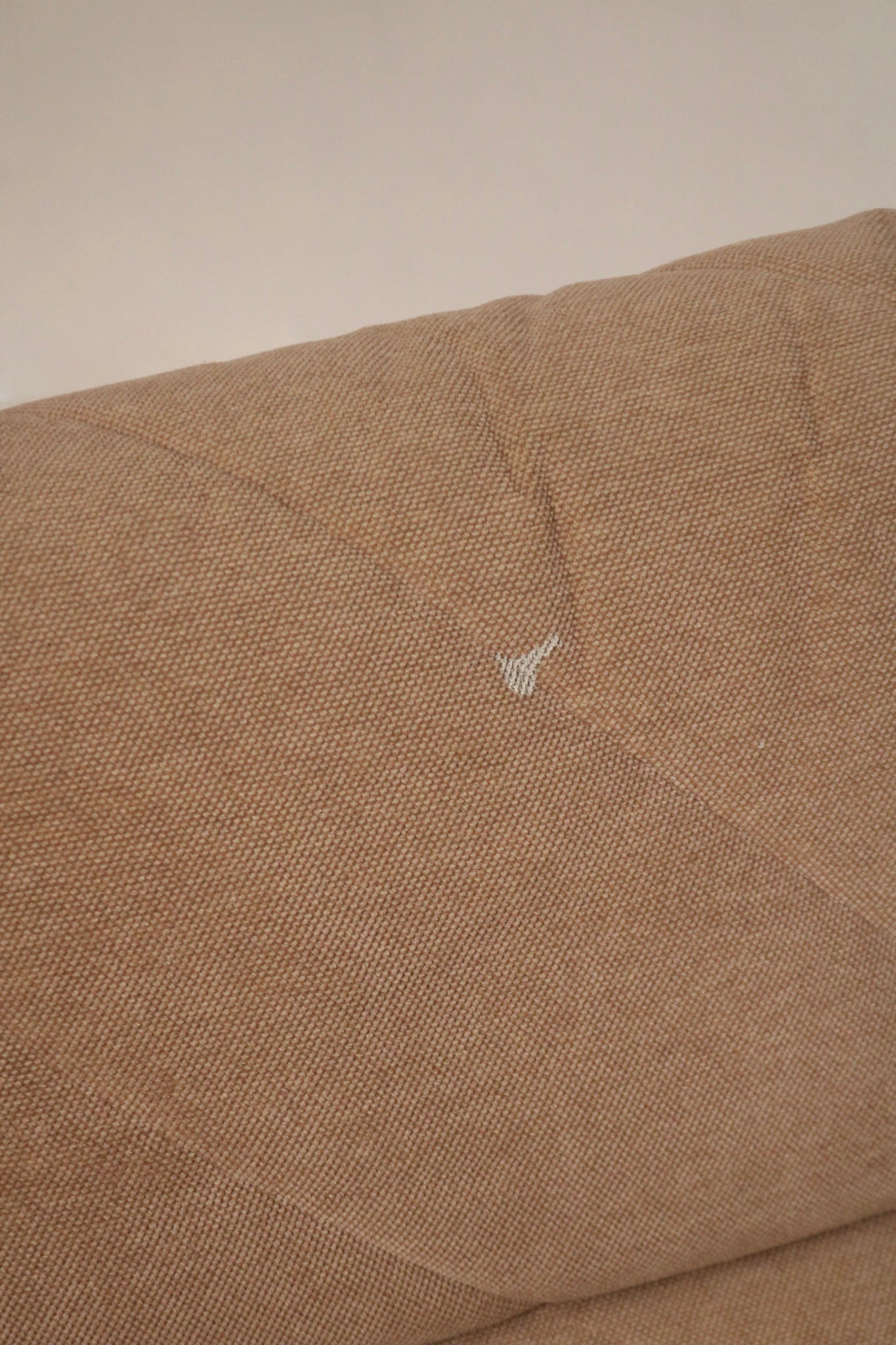 Detail shot of seat cushion edge on fabric modular sofa showing piping, seam construction and plush fabric surface in brown-pink material