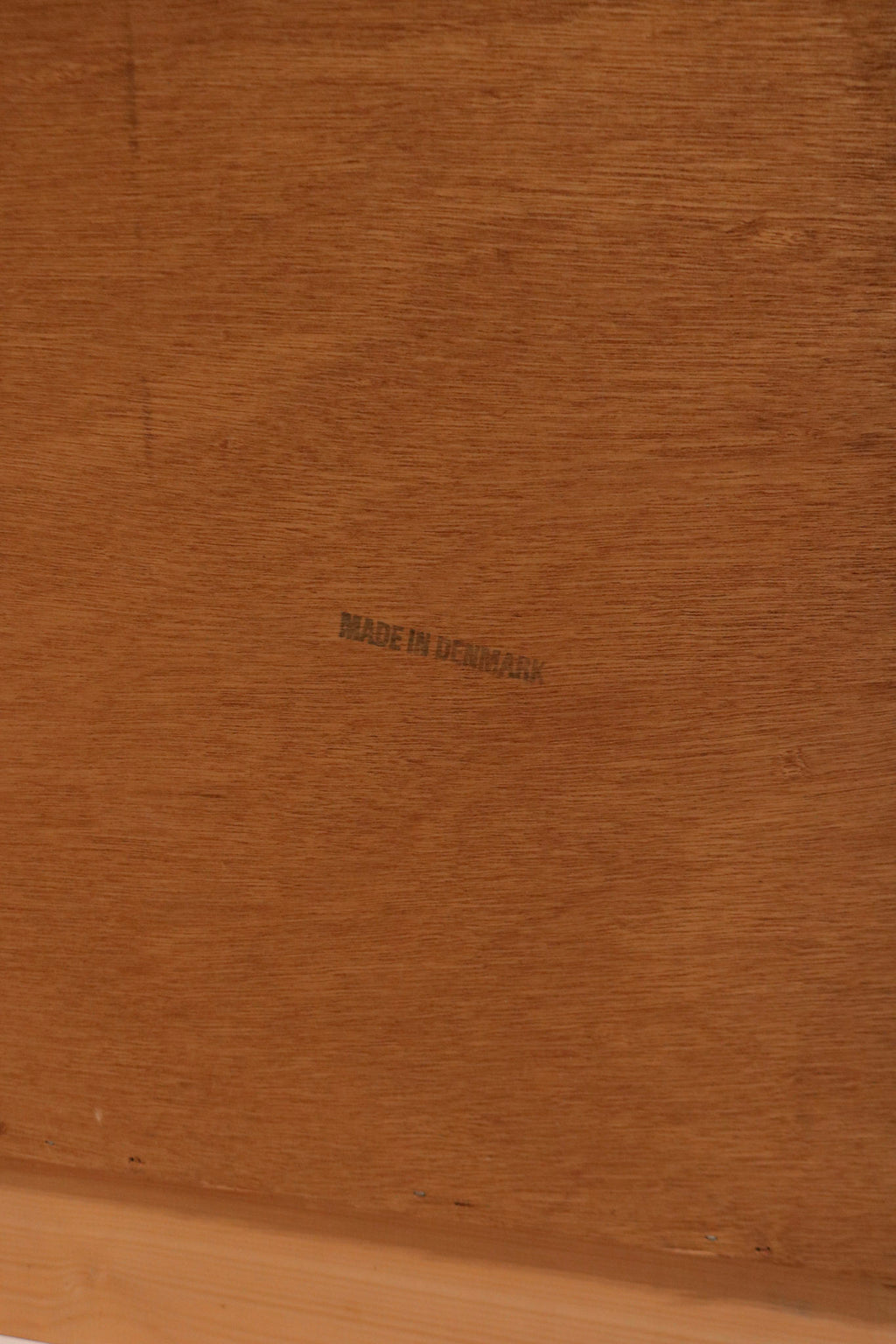 Detail of natural teak color and sheen under light on the dresser surface