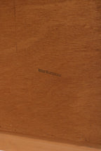 Detail of natural teak color and sheen under light on the dresser surface