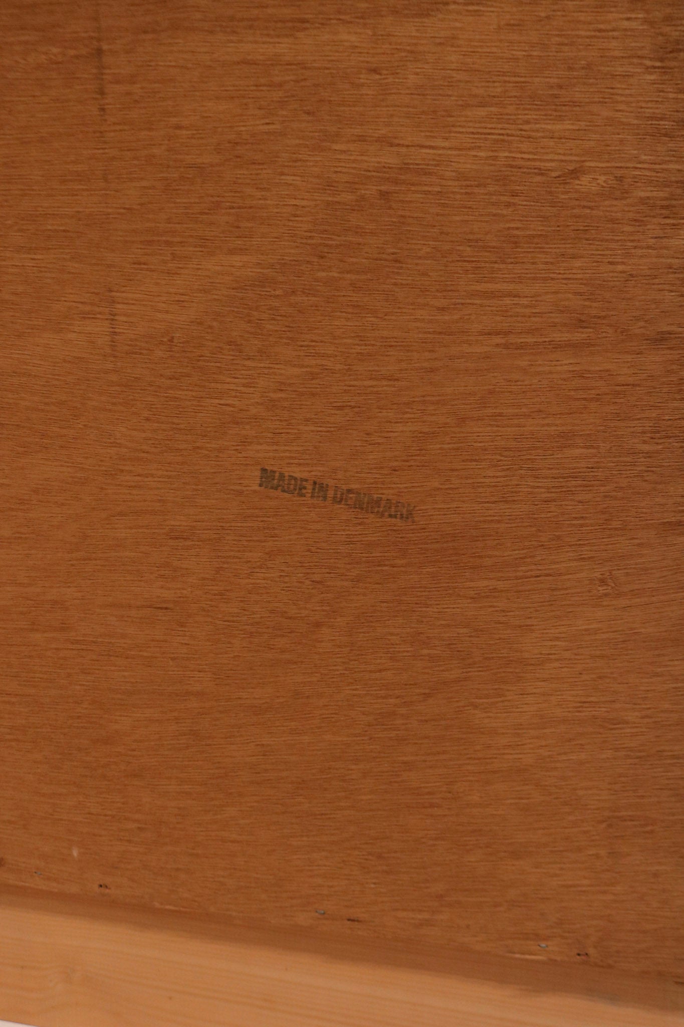 Detail of natural teak color and sheen under light on the dresser surface