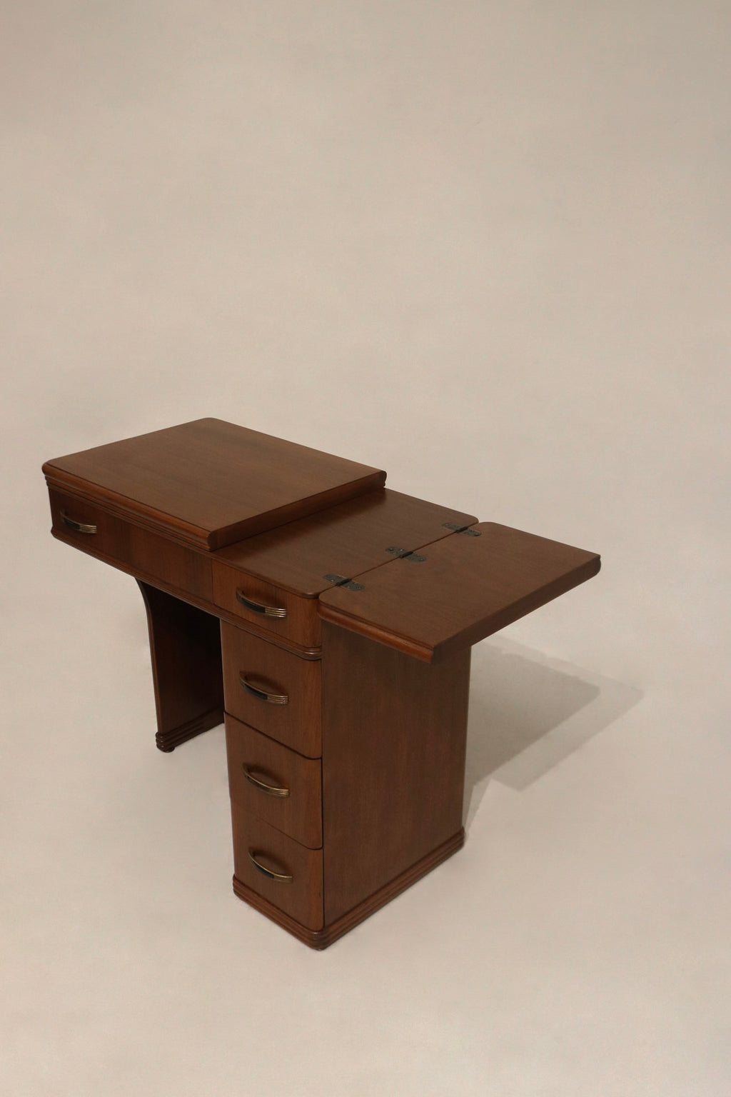 Detail: close-up of drawer hardware on walnut wood desk, metal handles with one missing black plastic part and working drawers