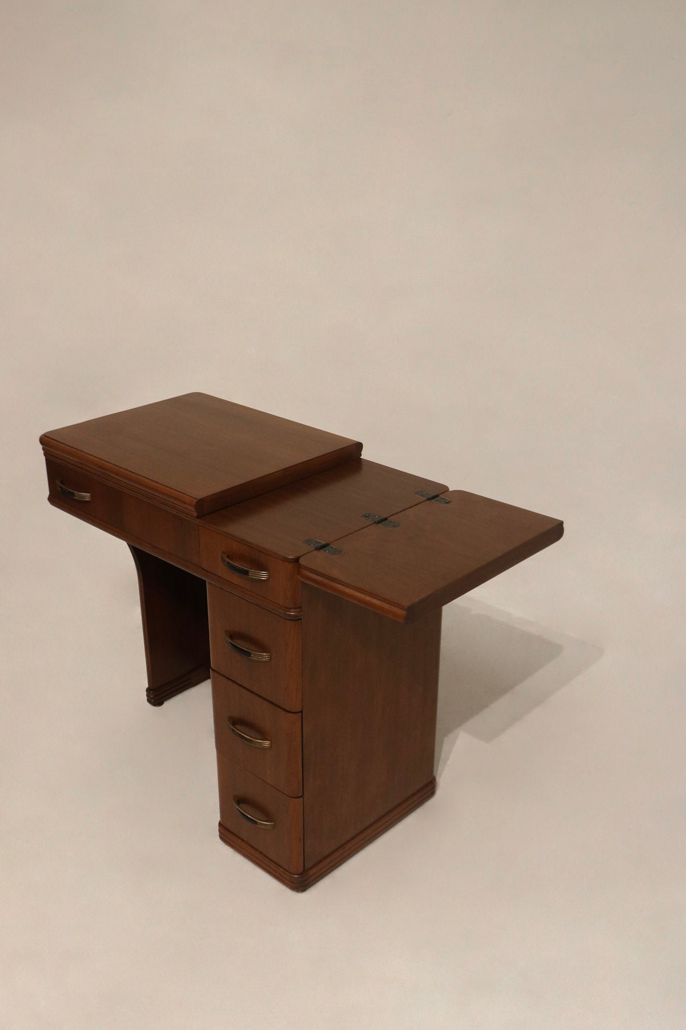 Detail: close-up of drawer hardware on walnut wood desk, metal handles with one missing black plastic part and working drawers