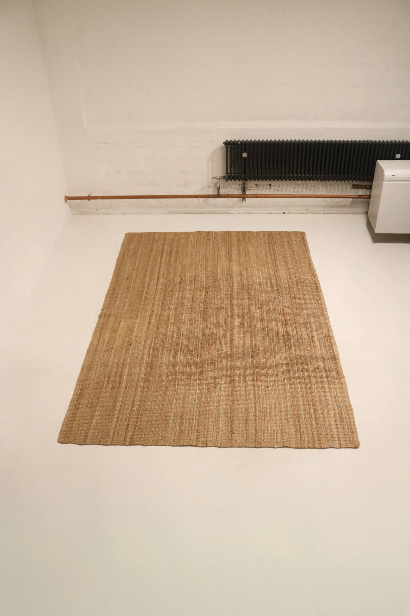 Angled image showing the soft natural tones and boho contemporary style pattern of the jute rug